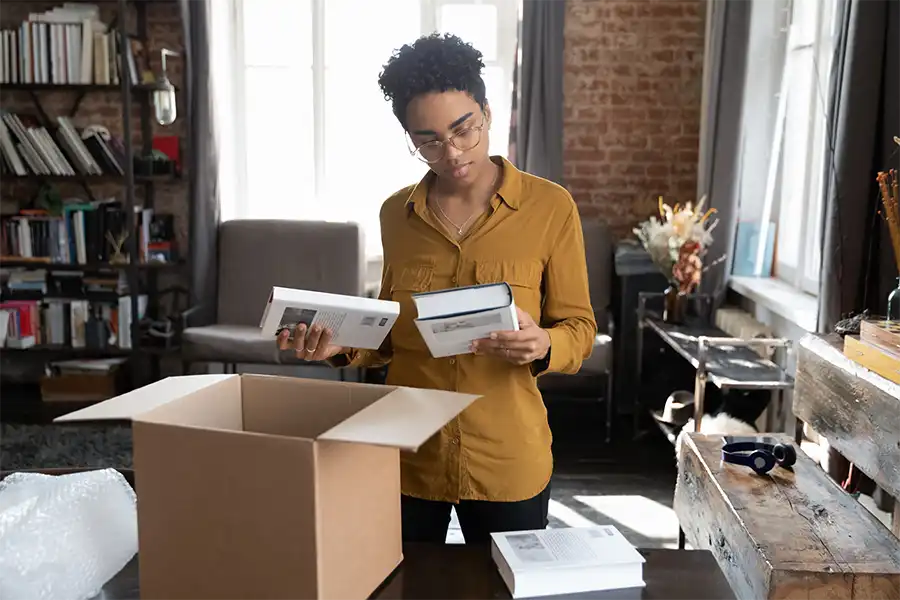 a woman unboxing books out of a large cardboard box